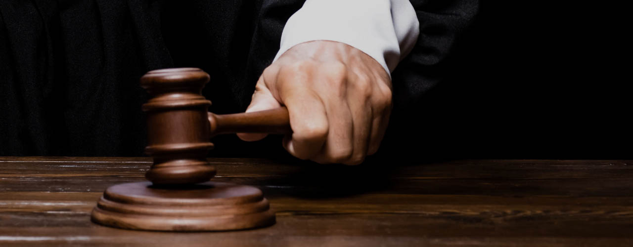 A closeup of a person striking a sounding block with a gavel.
