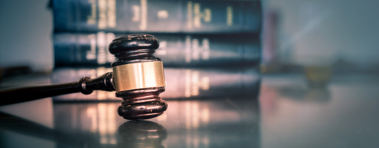 A gavel sitting in front of a stack of books.